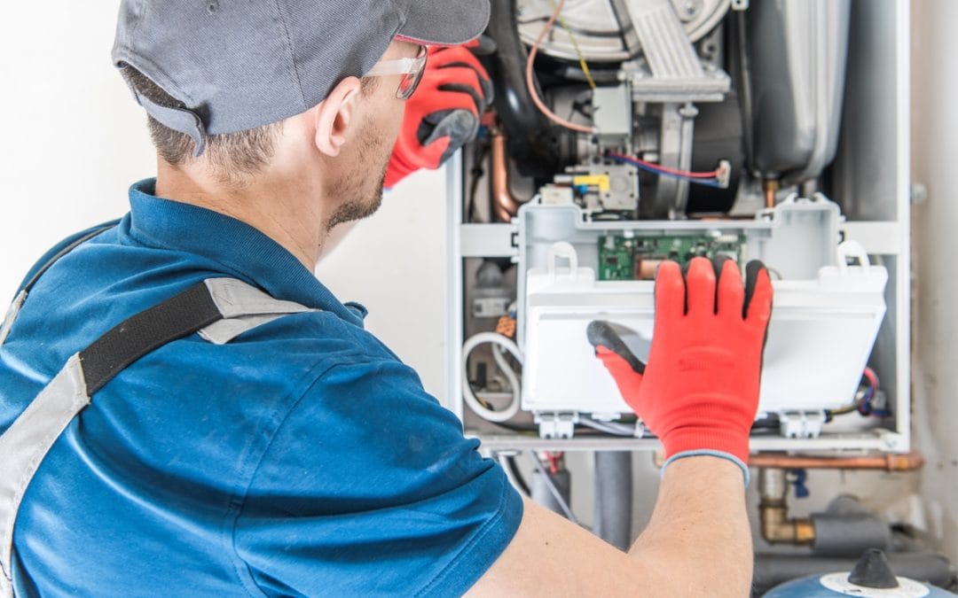 Furnace Repair Technician in a blue uniform and red gloves repairing a gas furnace, focusing on the internal components.