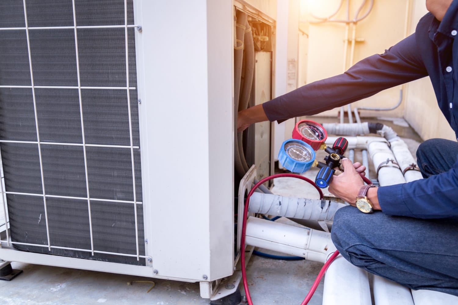 2762 Technician checking an outdoor air conditioning unit with pressure gauges and tools.