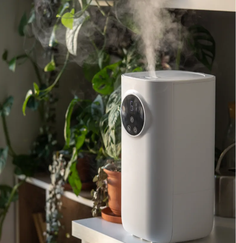 A white humidifier emits mist on a table surrounded by potted plants in a sunlit room.