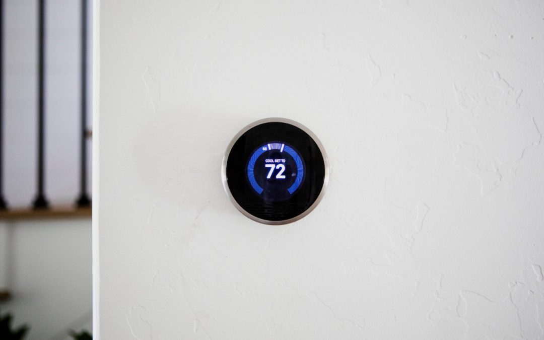 A digital thermostat on a white wall displays a set temperature of 72 degrees.
